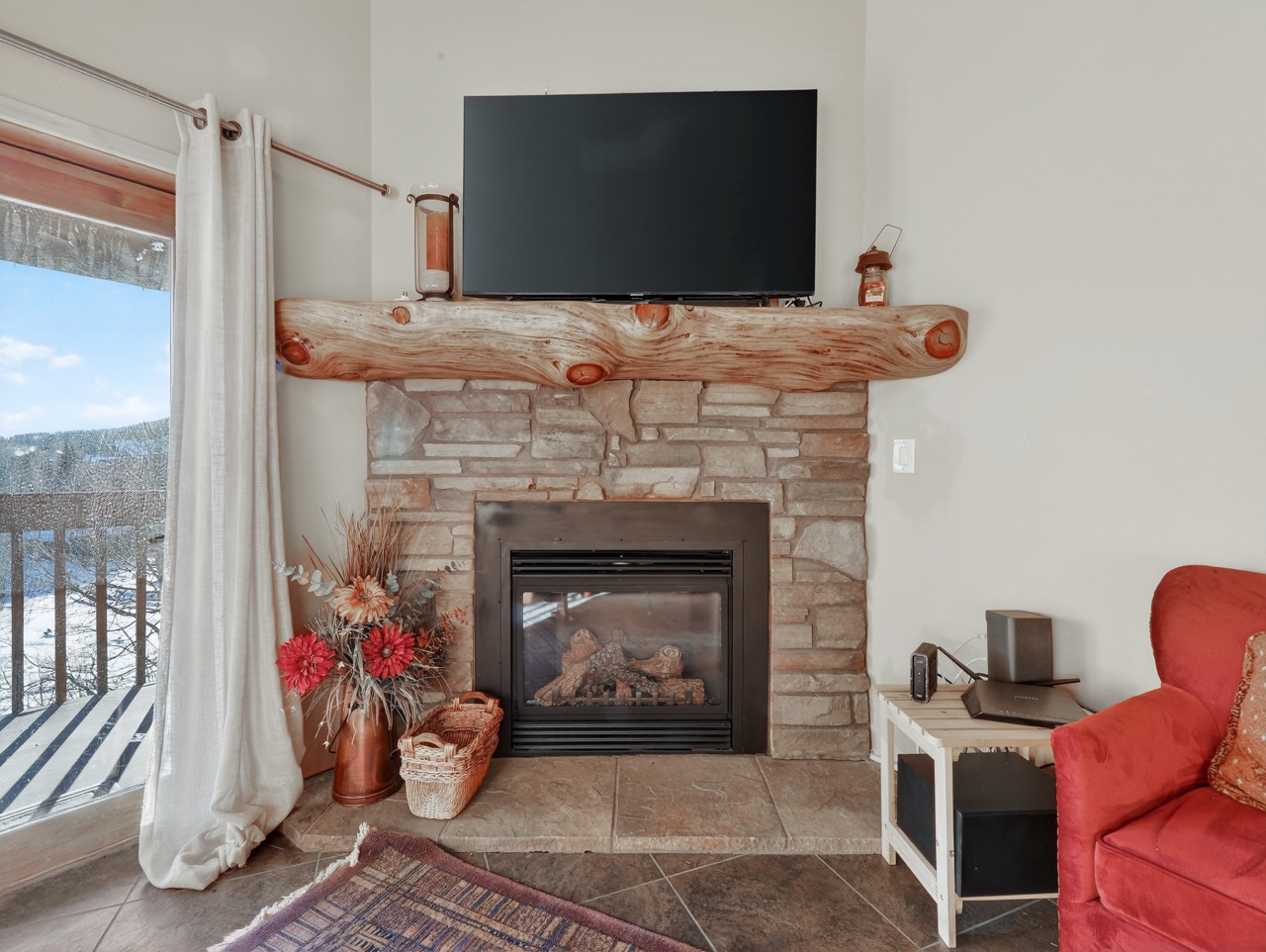 Cozy up by your stone fireplace while enjoying mountain views through oversized windows in this welcoming living space.
