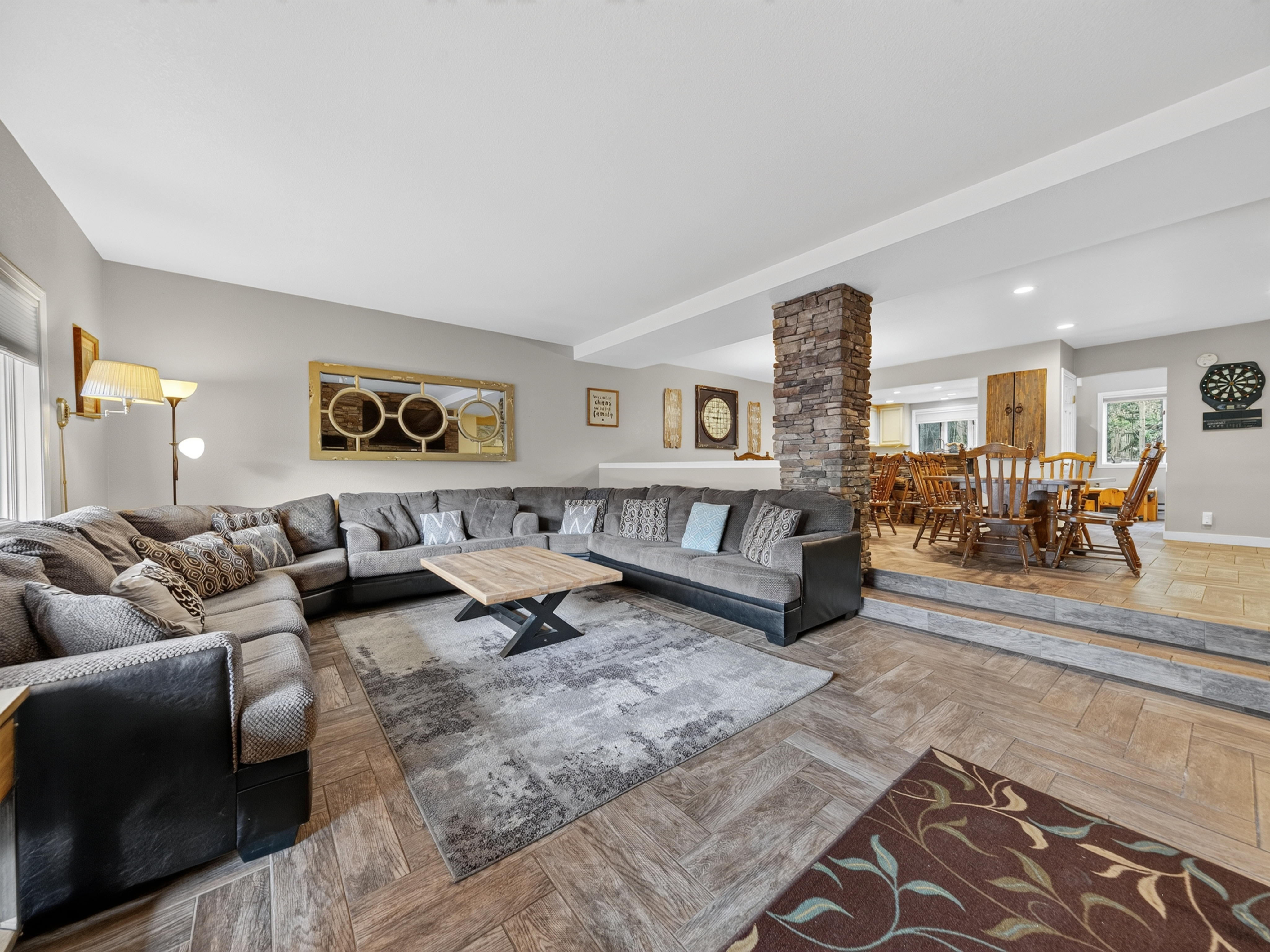 Gather your group around the plush sectional in this spacious living area, where rustic stone fireplace and open-concept design create the perfect setting for memorable conversations and cozy evenings together.
