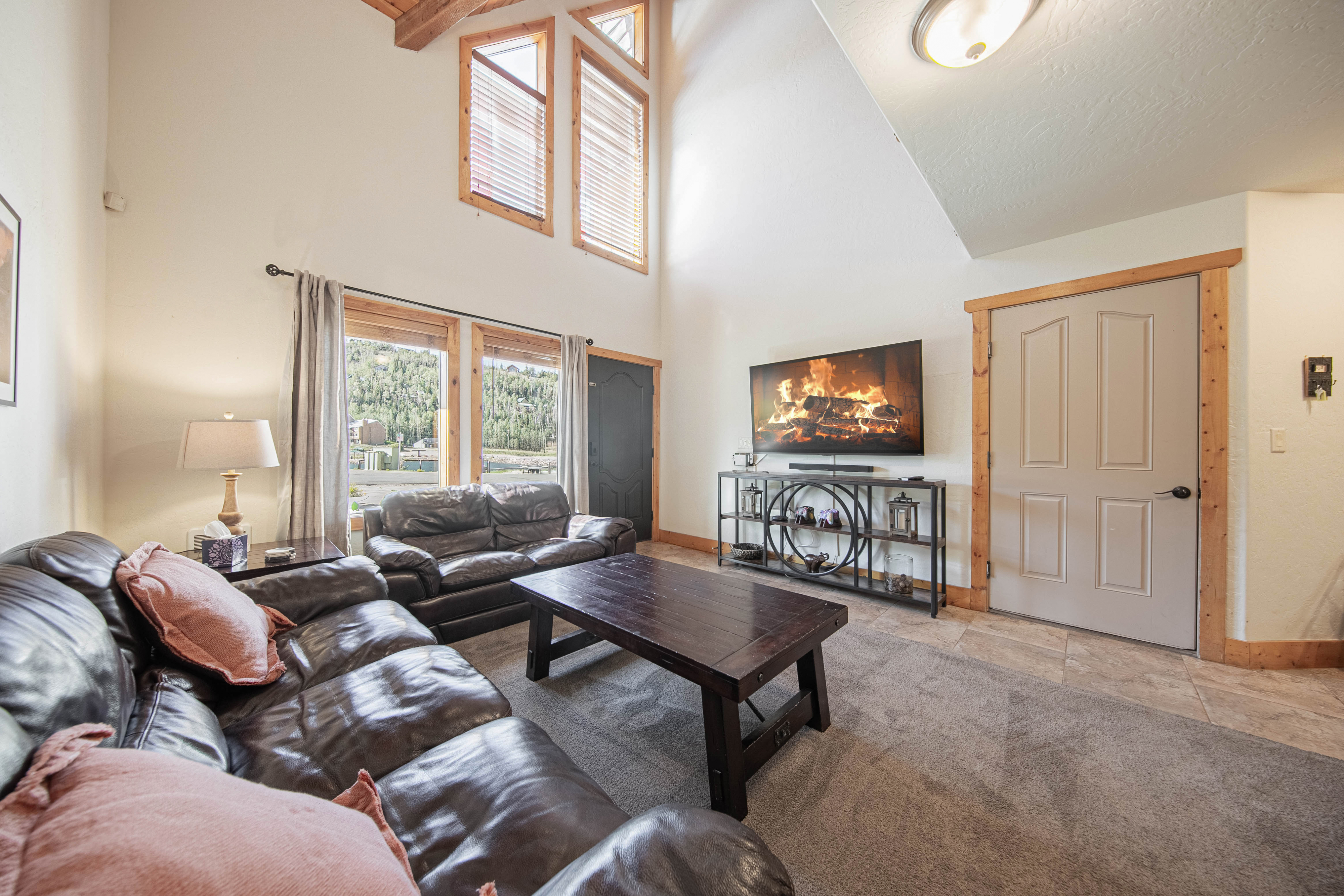 Sink into plush leather sofas beneath soaring vaulted ceilings, where natural light pours through tall windows and warm wood accents create your perfect mountain retreat.