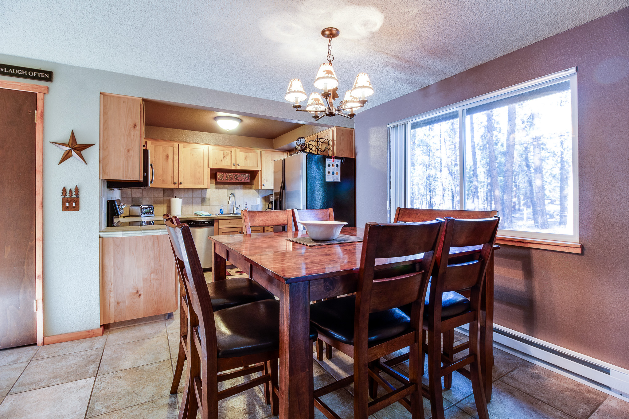 Gather around this inviting dining table with snowy forest views just beyond the window, perfect for cozy meals after a day of mountain adventure.
