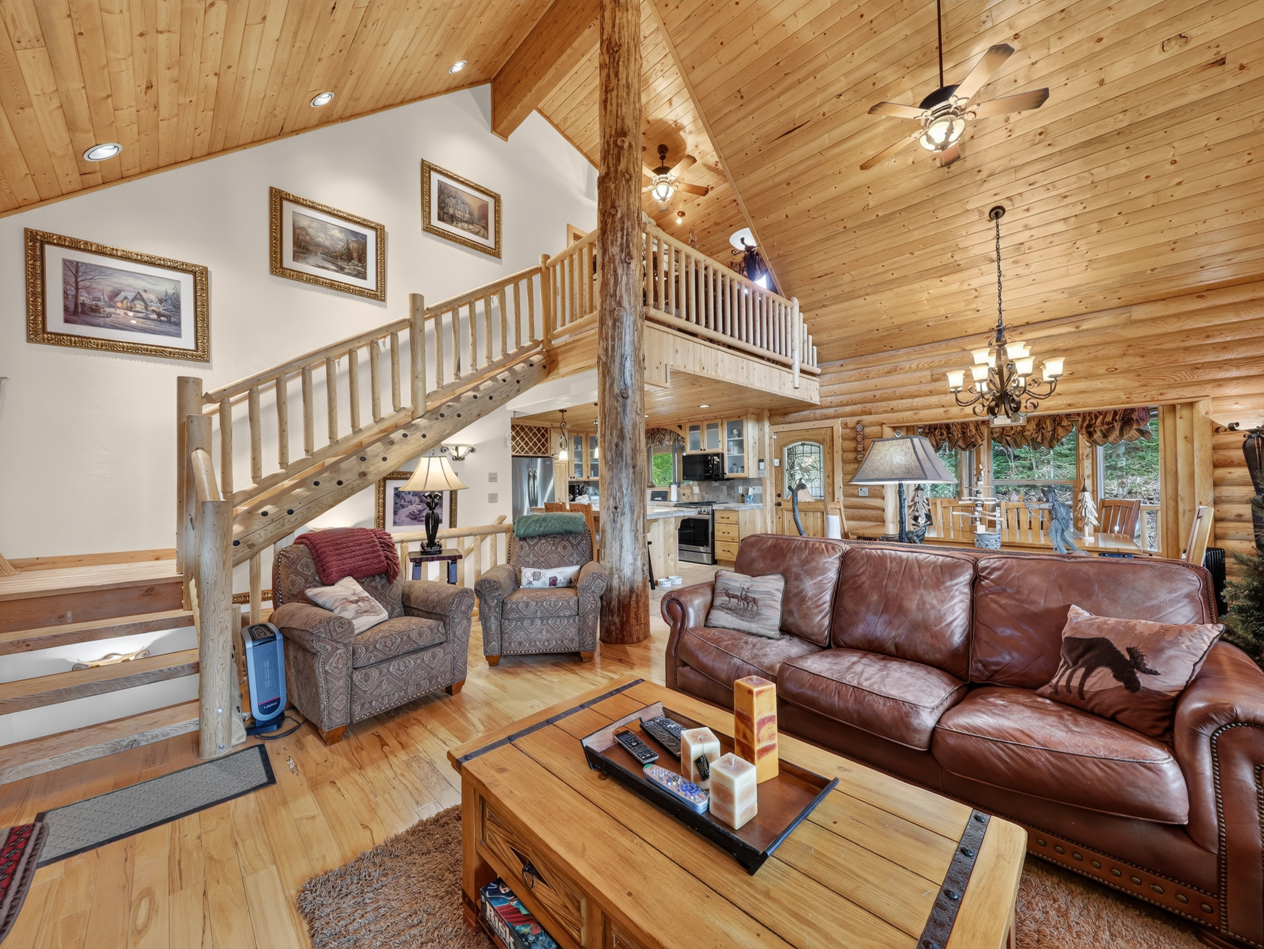 Sink into the plush leather sofa and take in the soaring wood-beamed ceilings, rustic log accents, and warm glow of natural light streaming through the windows—your perfect mountain escape.