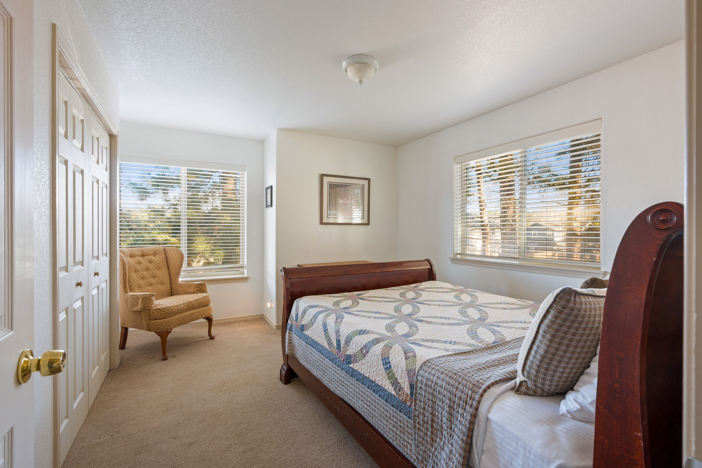 Unwind in your peaceful bedroom with natural light streaming through windows and a cozy reading chair for quiet moments.