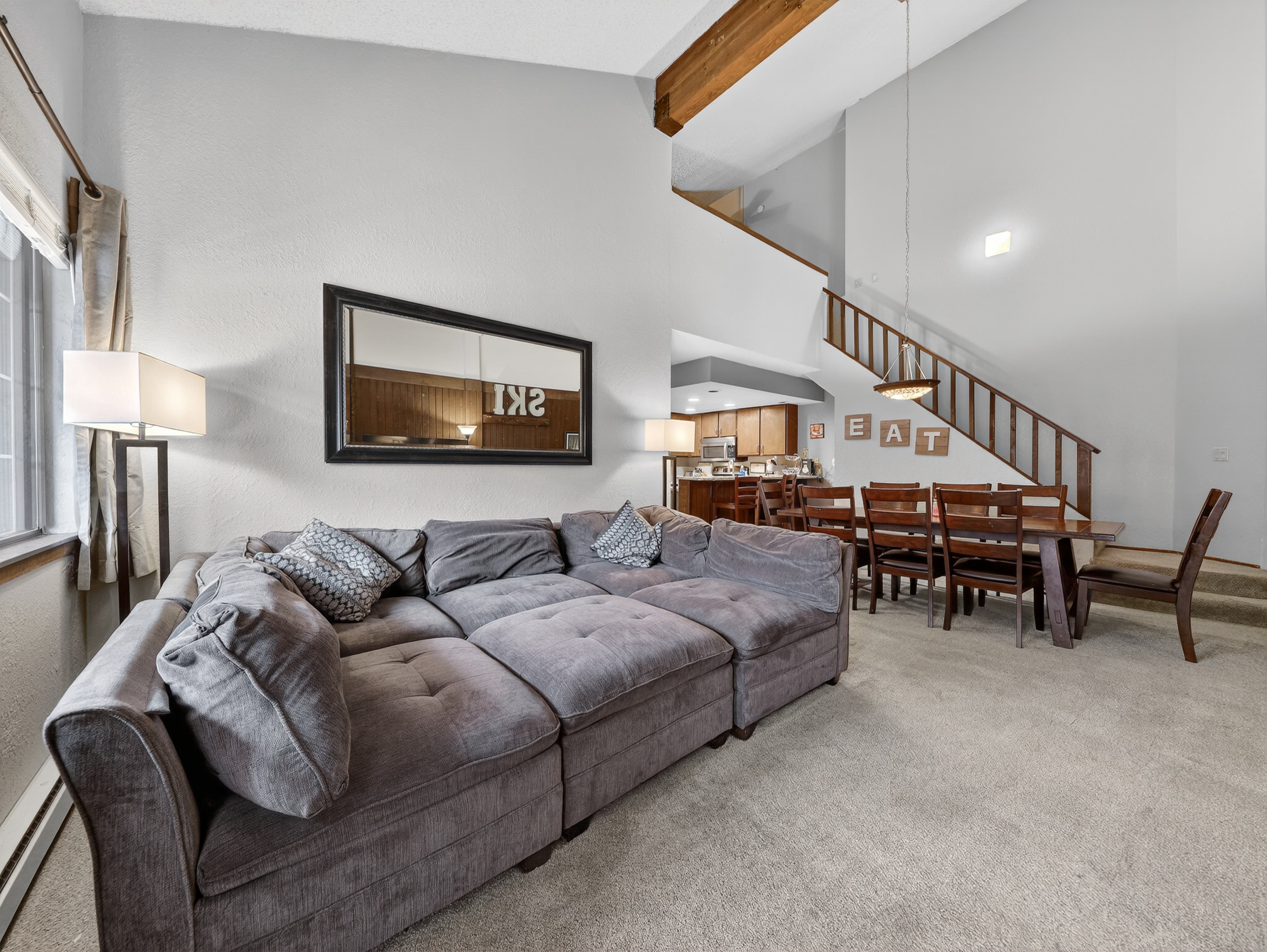 Relax in your spacious living area with plush sectional seating, high ceilings, and warm wood accents creating the perfect gathering space.