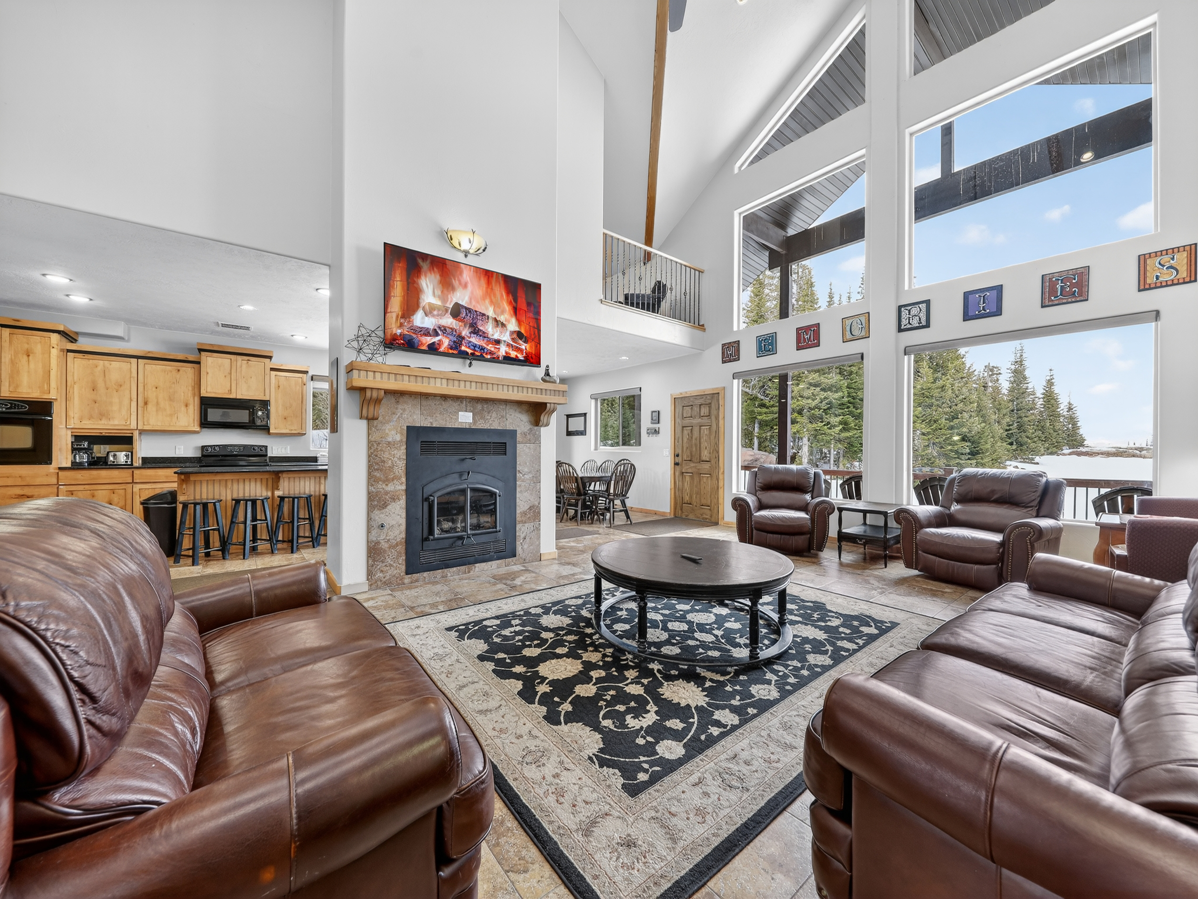 Relax in this spacious living room with soaring ceilings, cozy fireplace, and panoramic mountain views through floor-to-ceiling windows.