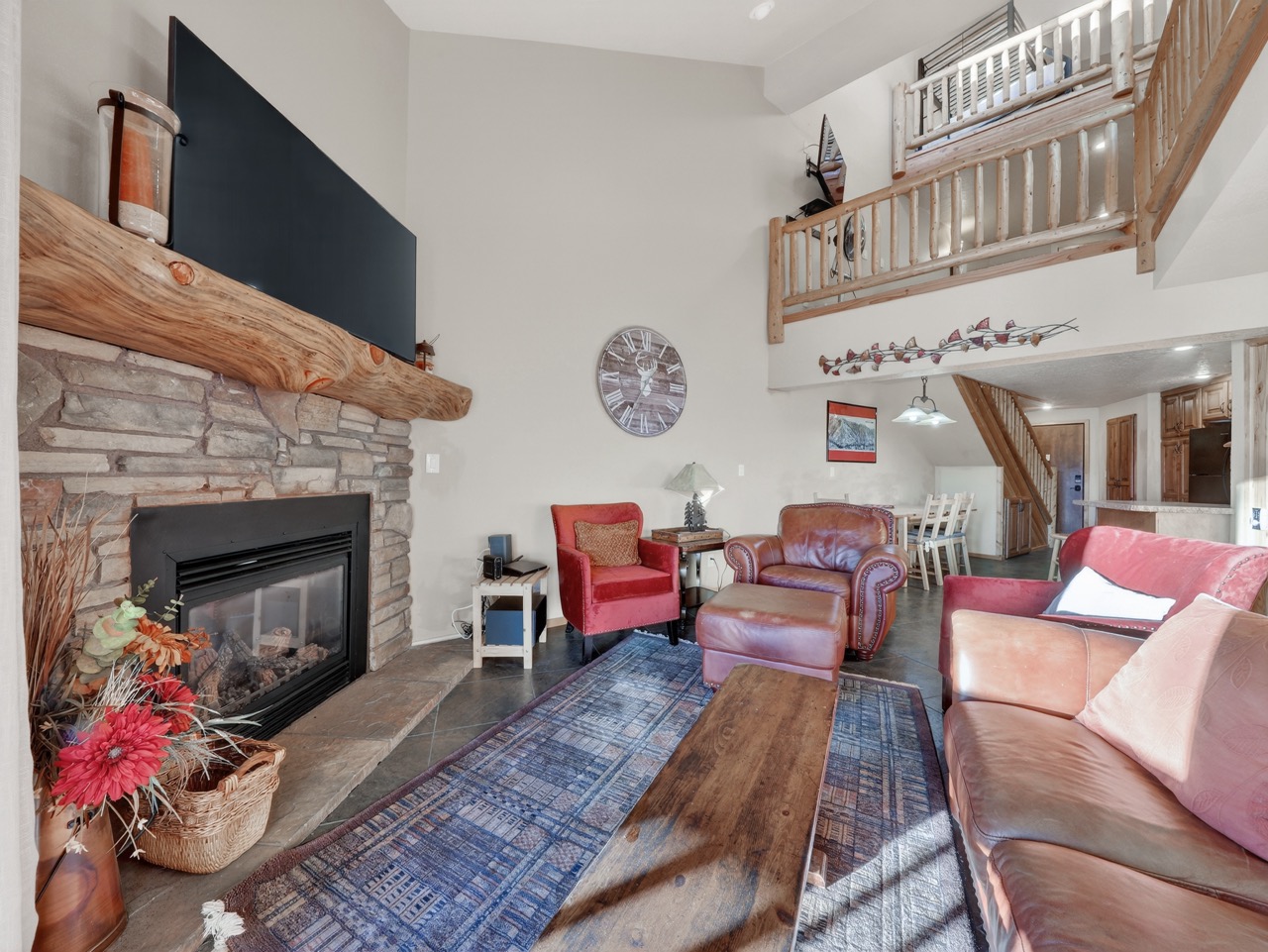 Relax in this spacious living room featuring rich leather seating, a crackling stone fireplace, and elegant loft views.