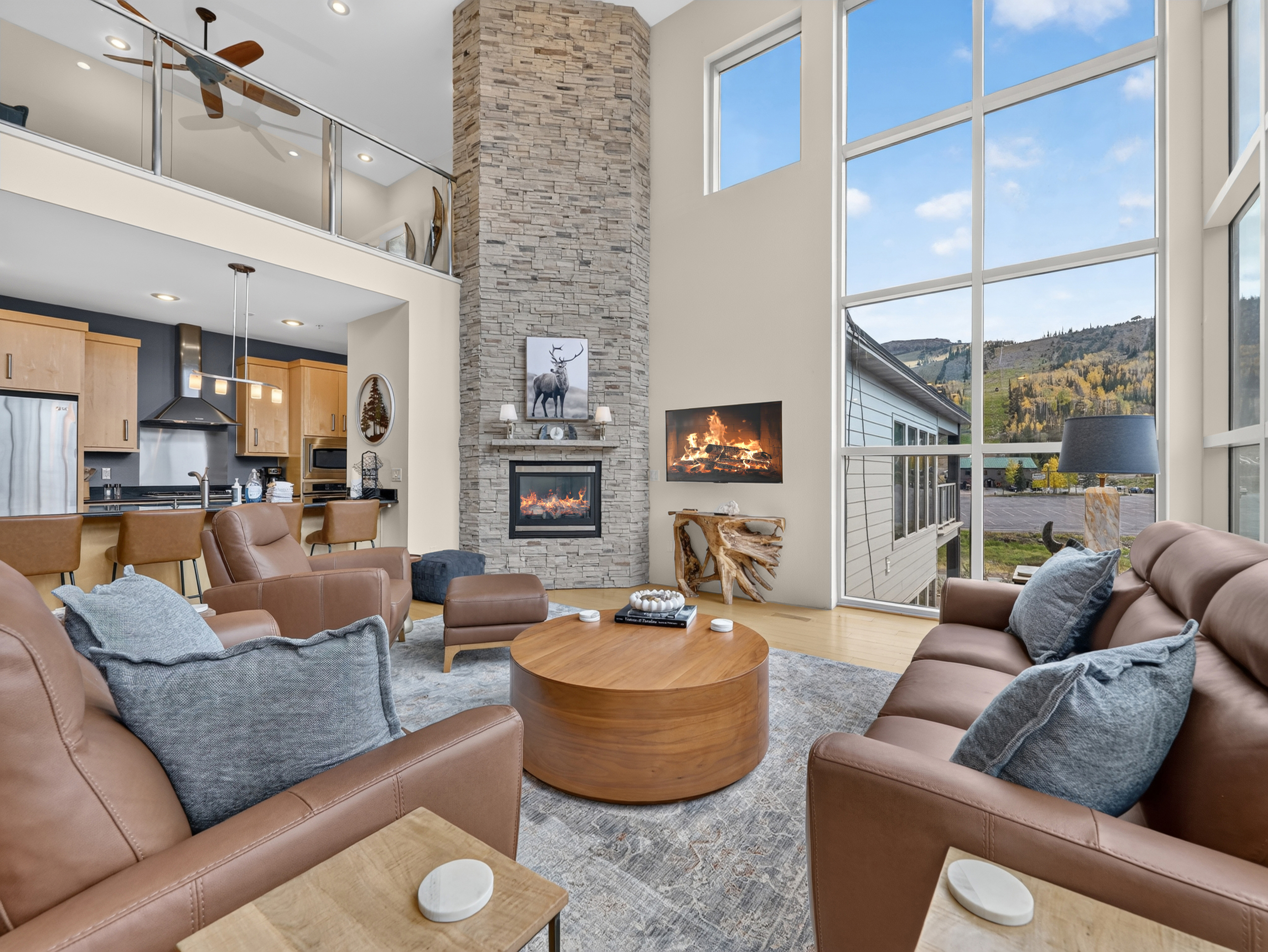 Sink into plush leather sofas by the glowing stone fireplace, where floor-to-ceiling windows frame breathtaking mountain views and fill the space with natural light.