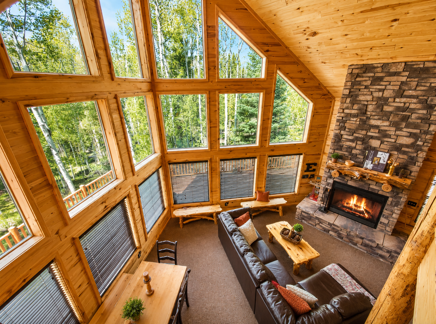 Relax in your vaulted living room with soaring windows framing lush forest views. Sink into the leather sofa, feel the warmth of the stone fireplace, and let nature surround you.