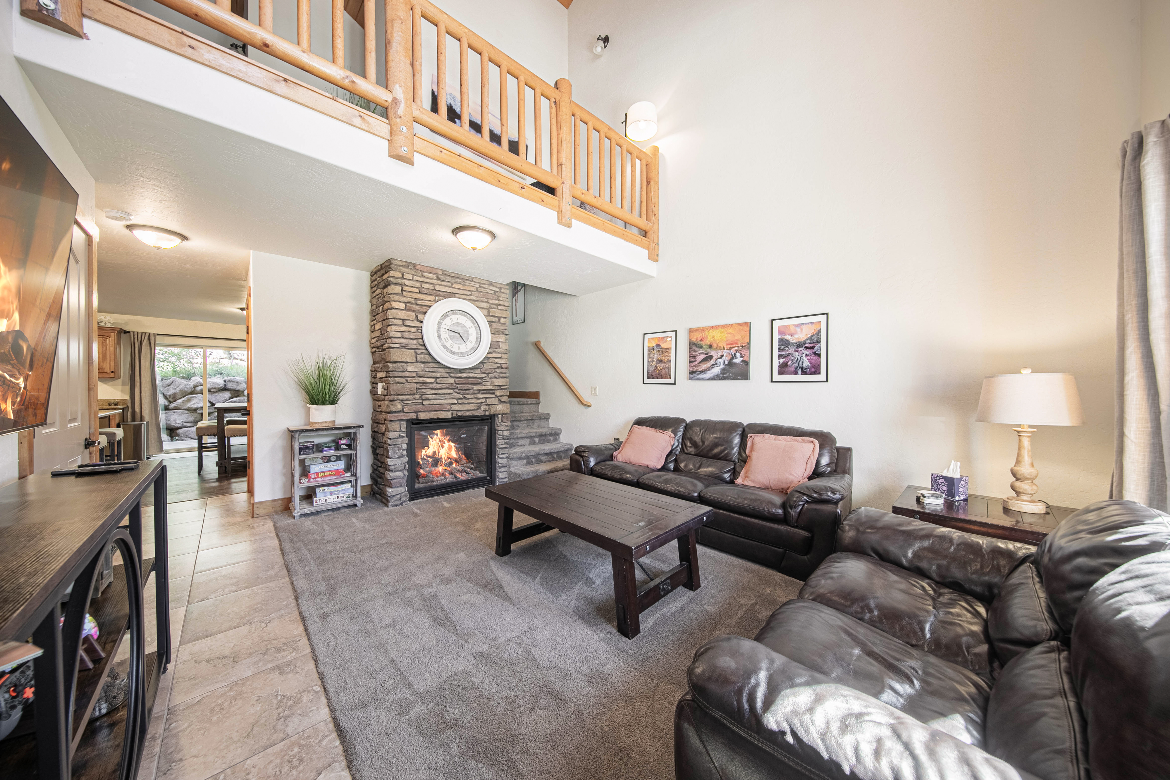 Unwind in your spacious living room with vaulted ceilings and a cozy stone fireplace crackling warmth into the open-concept space. Sink into plush leather seating and let the mountain retreat vibes wrap around you.