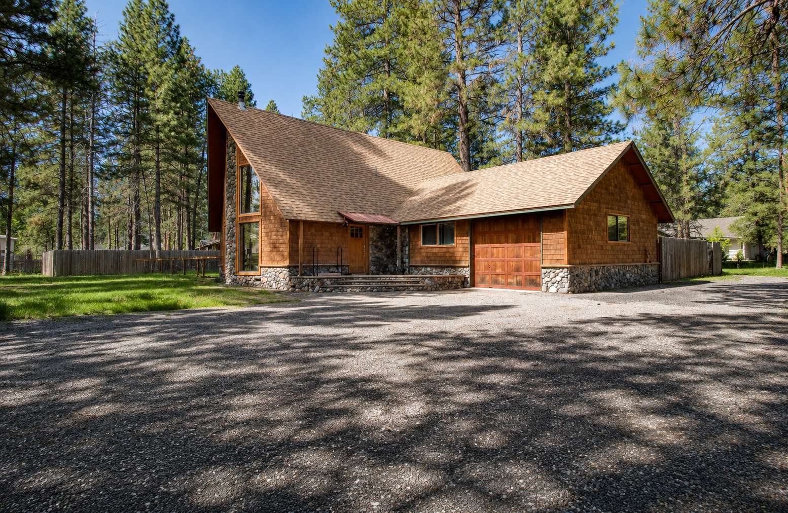 A welcoming cedar-shingled mountain retreat nestled among towering pines, featuring stone accents and a spacious driveway with ample parking for your stay.