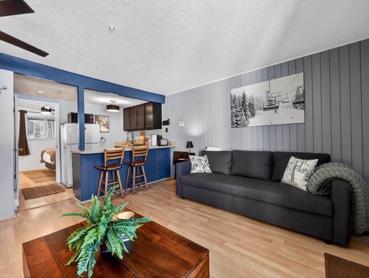 Relax in your cozy living space with mountain lodge charm, featuring a comfy sofa and open kitchen perfect for après-ski gatherings.