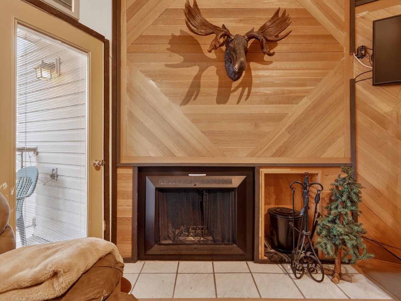 Cozy up by your rustic fireplace, where warm wood paneling and mountain charm create the perfect cabin retreat atmosphere.