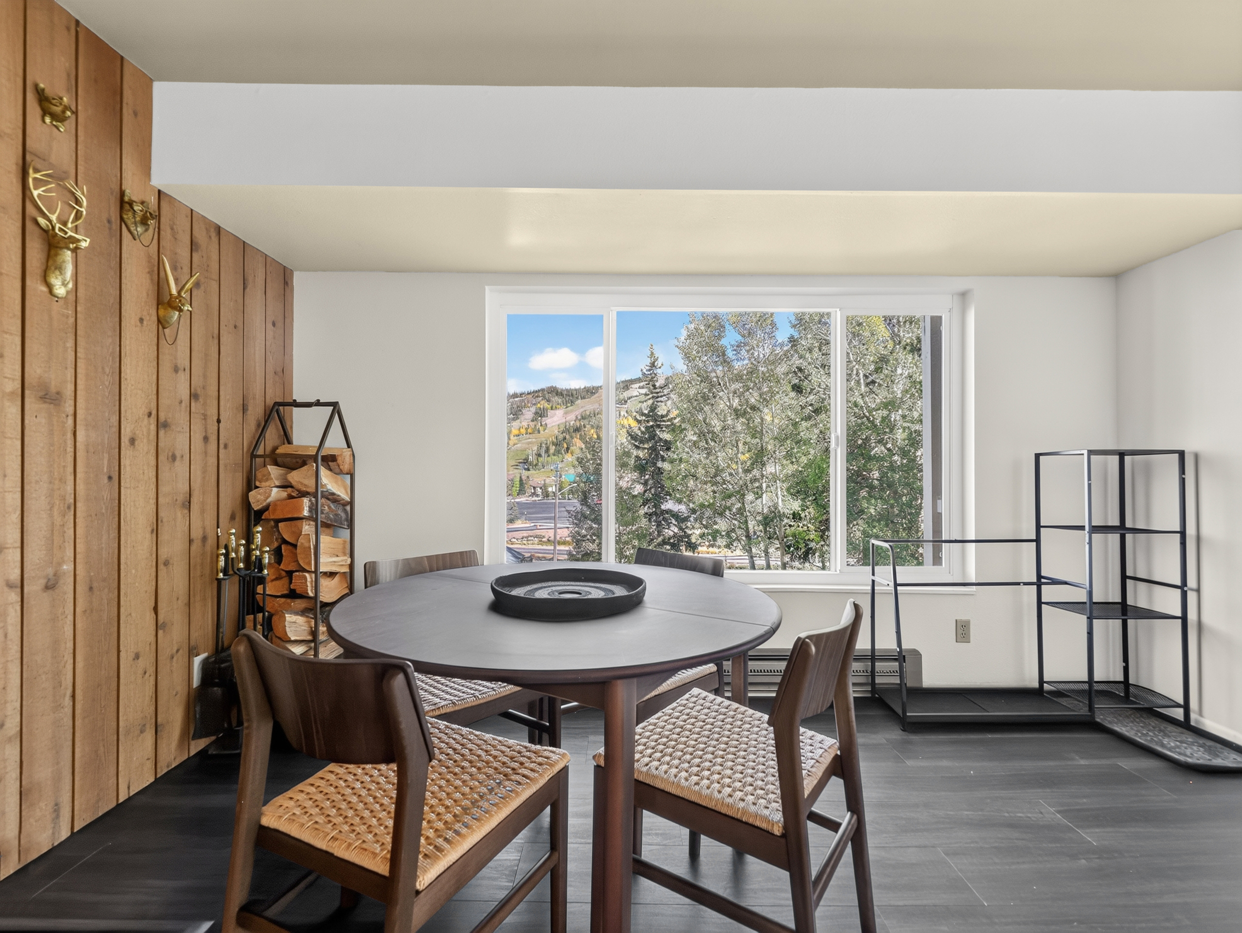 Gather around your dining table framed by bright windows that reveal the natural beauty just beyond. Sunlight pours in, highlighting warm wood accents and inviting you to linger over meals while soaking in peaceful views.