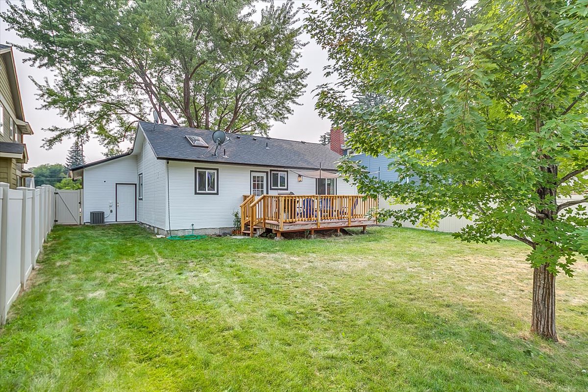 Charming property with spacious backyard and wooden deck, nestled among mature trees in a peaceful residential neighborhood.