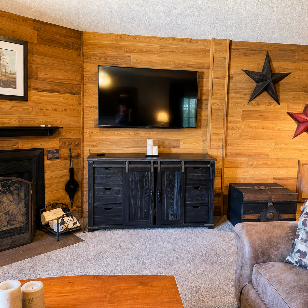Unwind in your cozy living room with warm wood-paneled walls, a crackling fireplace, and rustic charm that makes every evening feel like a retreat.