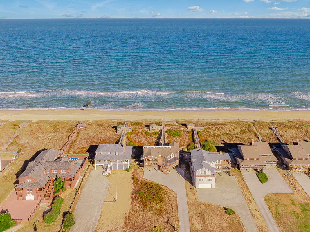 Aerial view of beachfront vacation properties positioned directly on the sandy shoreline with ocean access.