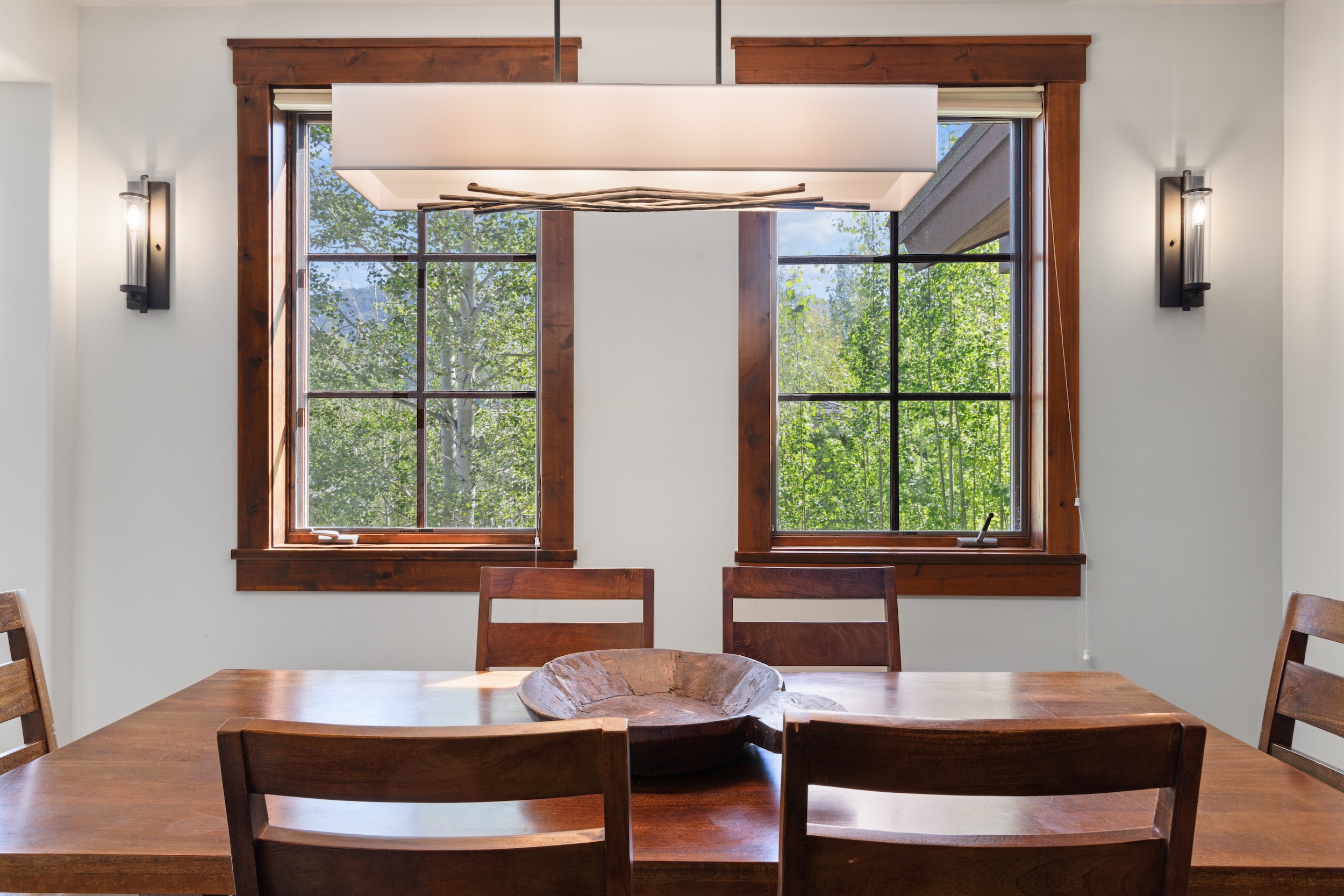 Gather around this warm wood table and enjoy meals with a serene forest view just beyond the windows—your perfect spot for morning coffee or evening conversations.