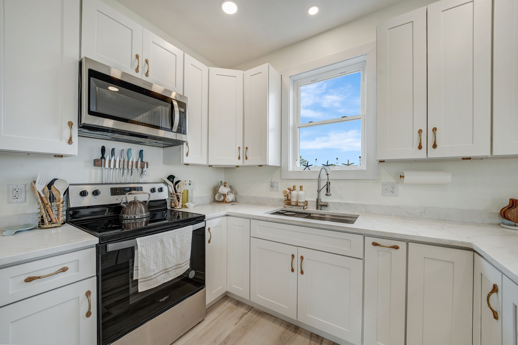 Stainless Appliances, beachy White Cabinetry, and Solid Surface Countertops.