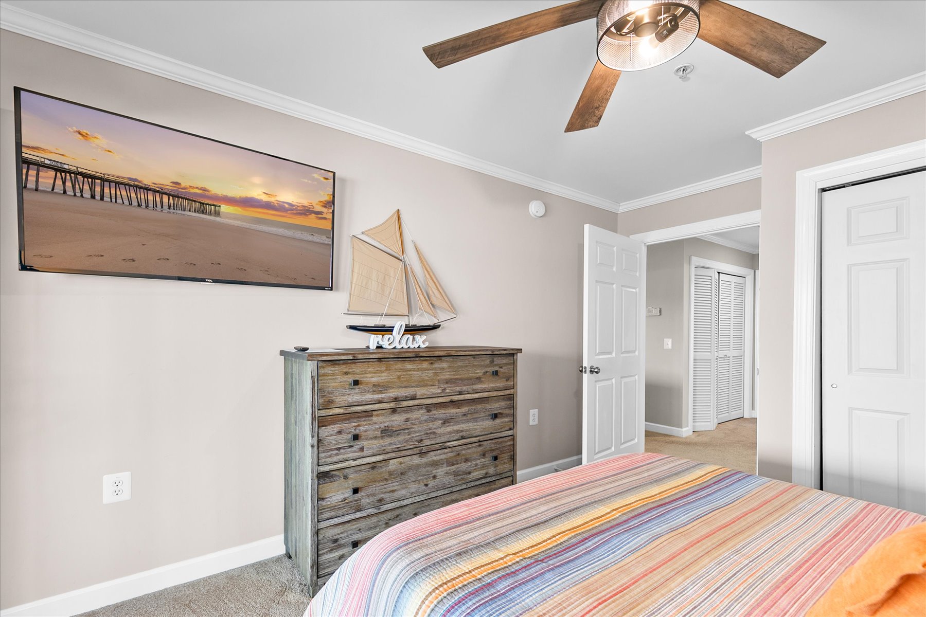 Unwind in your serene coastal bedroom with rustic wooden furniture, ceiling fan comfort, and charming nautical touches that whisk you away to seaside bliss.