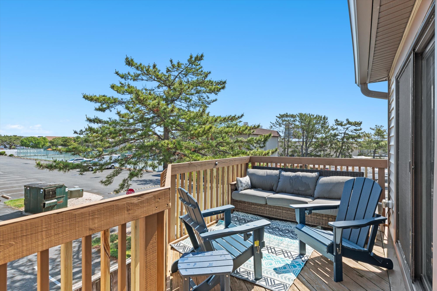 This elevated wooden balcony comes equipped with stylish Adirondack chairs and an outdoor sofa, making it the perfect spot to relax.