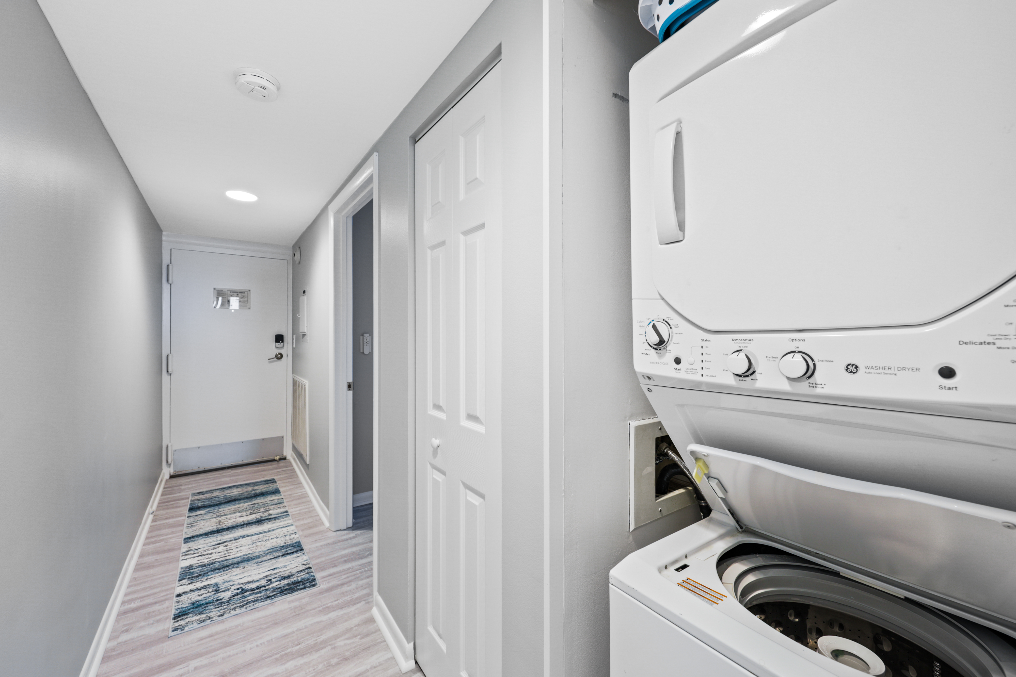 Stackable washer and dryer located in the hallway for your convenience.