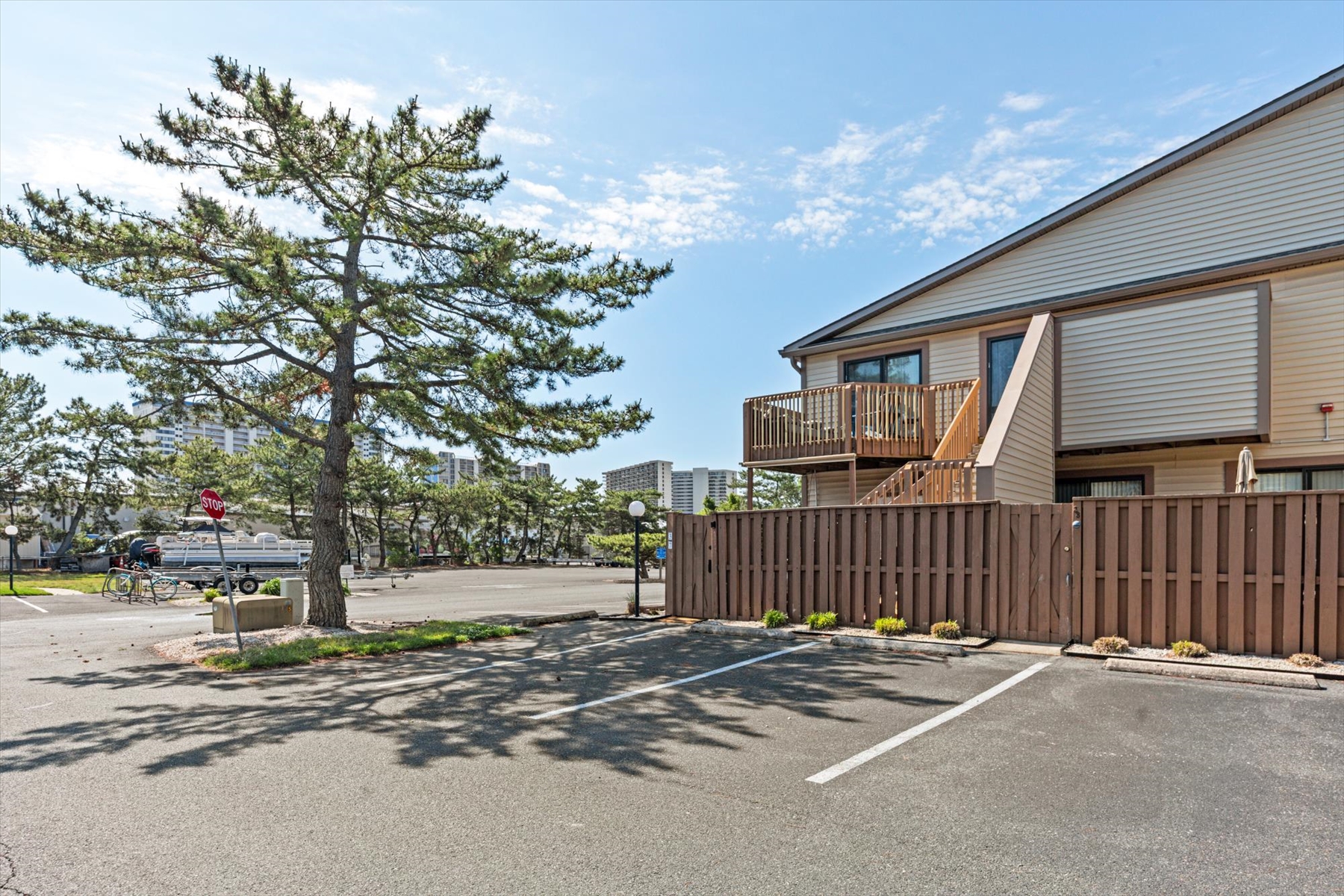 A bright daytime view showcasing the villa's private balconies and enclosed lower patio spaces from the parking area.