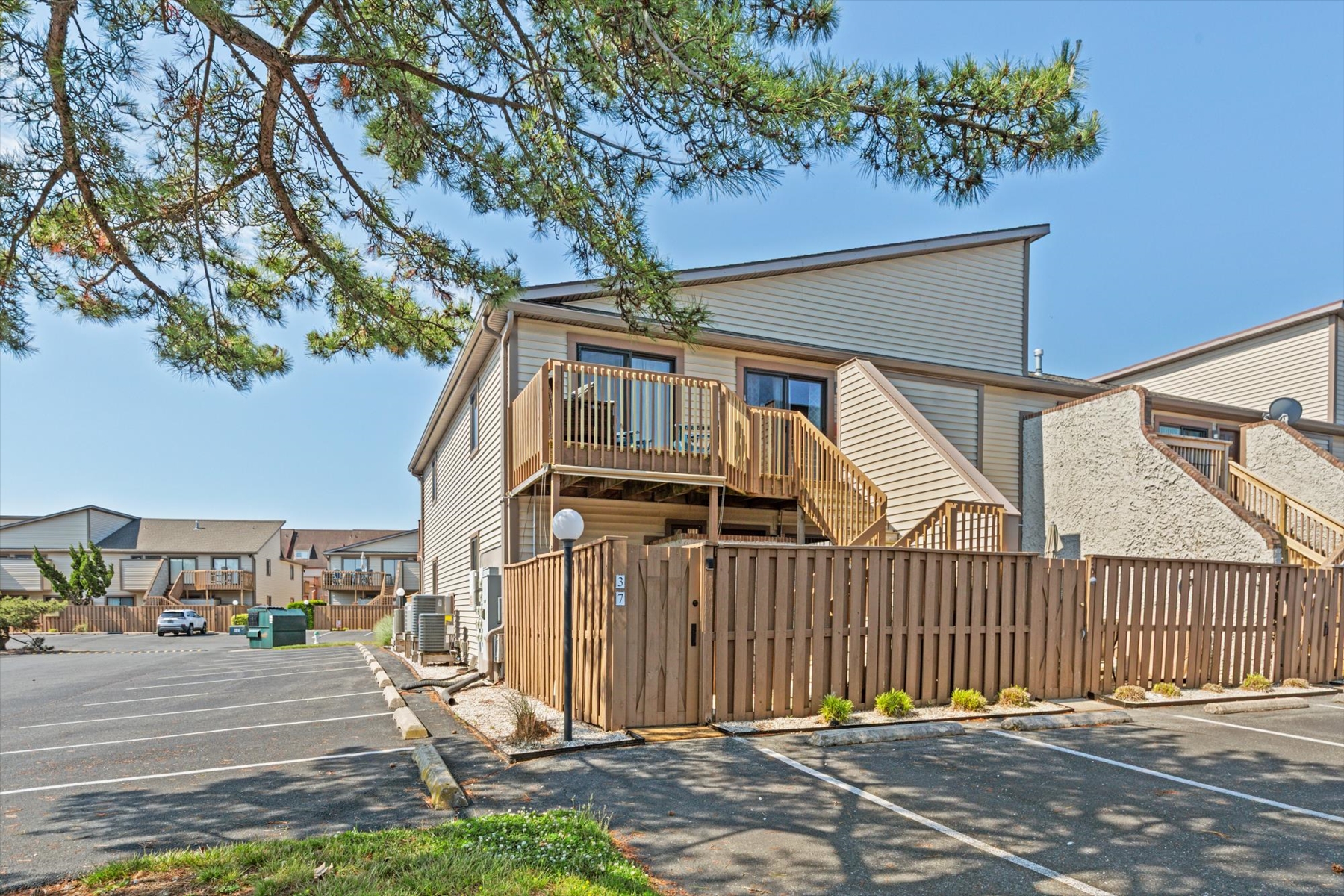 This close-up view highlights the private wood fenced lower courtyard and the upper balcony staircase design.