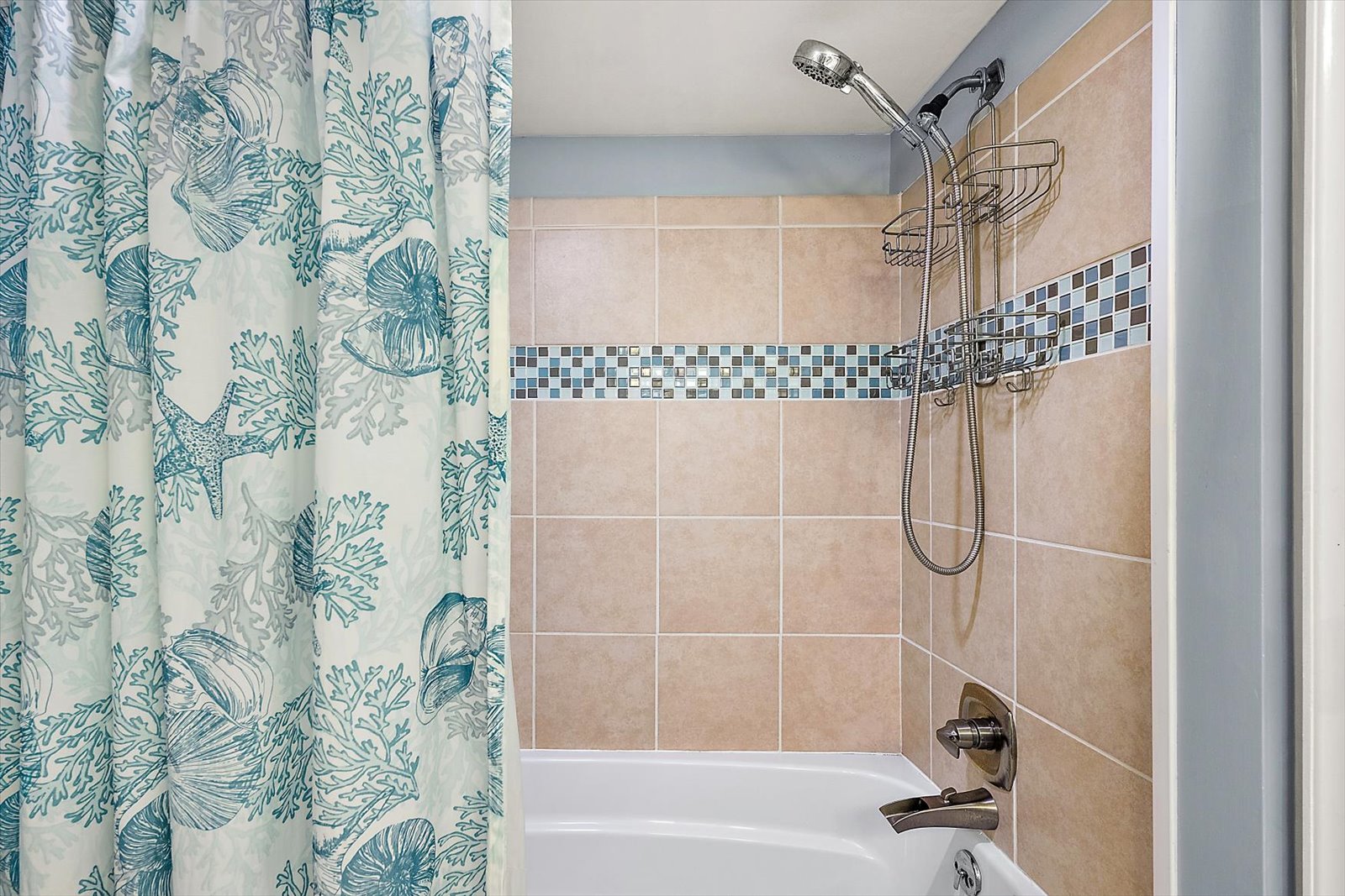 Soak away the day in this clean bathroom setup, featuring a beautifully tiled shower and tub enclosure with a decorative accent border.