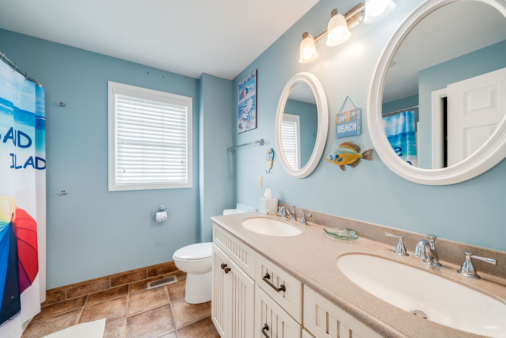 Step into your coastal-themed bathroom with double vanity, perfect for morning routines. Ocean-blue walls and beach decor create a relaxing seaside atmosphere.