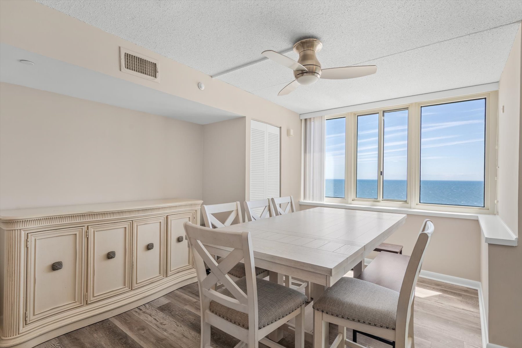 This welcoming dining space features a large table, custom built-in cabinetry, and wall-to-wall ocean views.