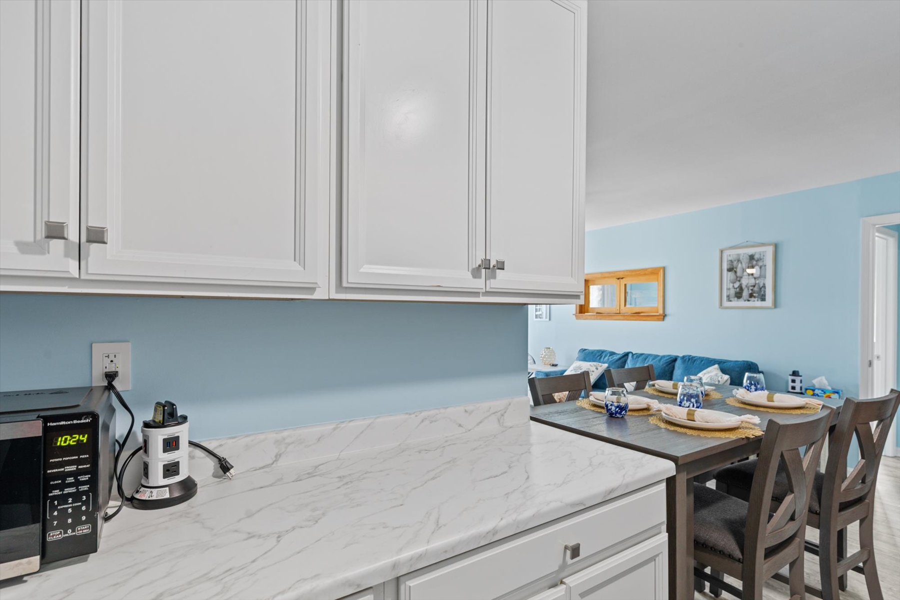 Additional clean, white countertop space on the opposite wall serves as an excellent spot for meal prep or serving buffet-style dinners.