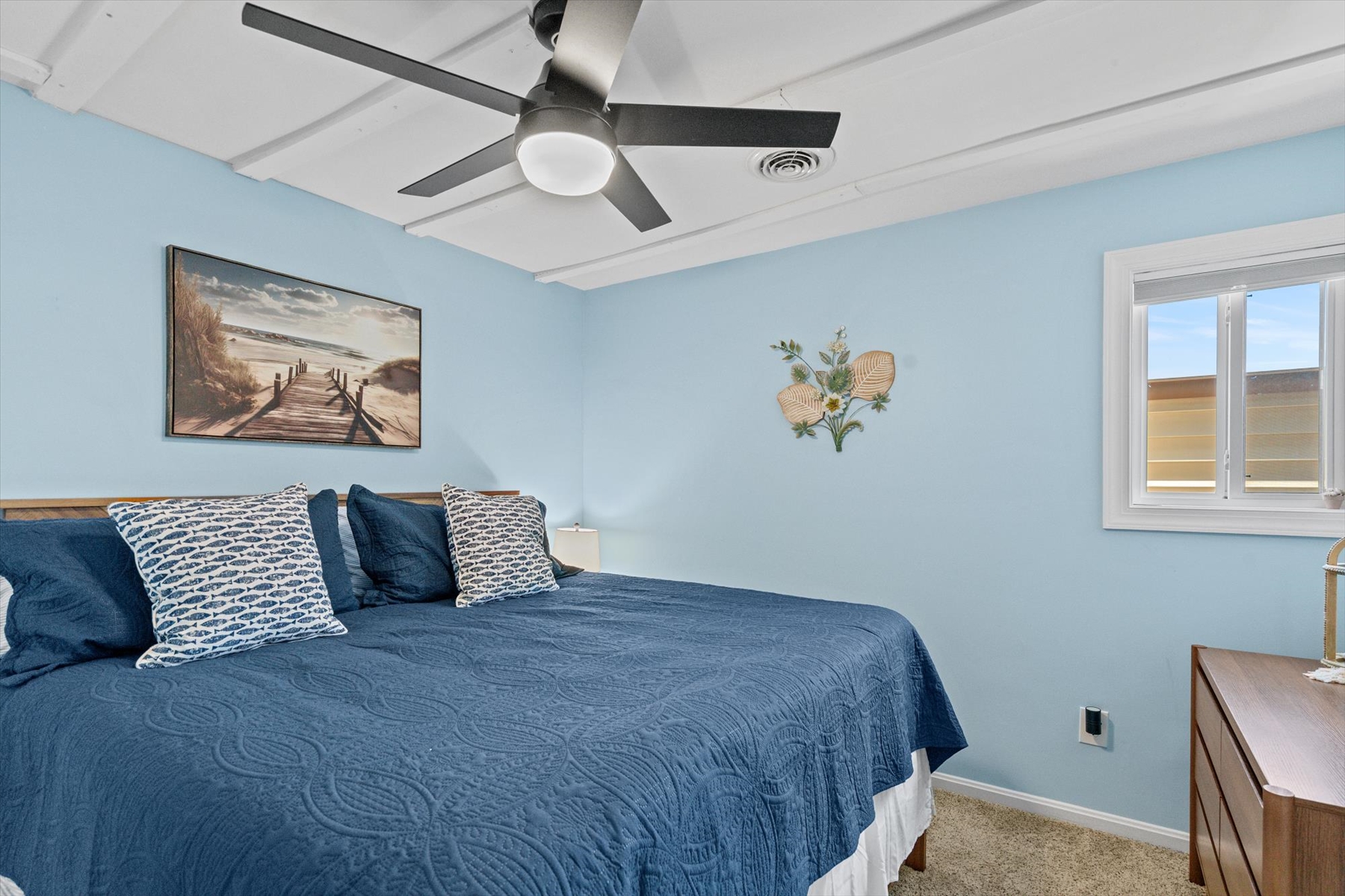 Cozy coastal wall art adds a touch of charm to this relaxing bedroom retreat.