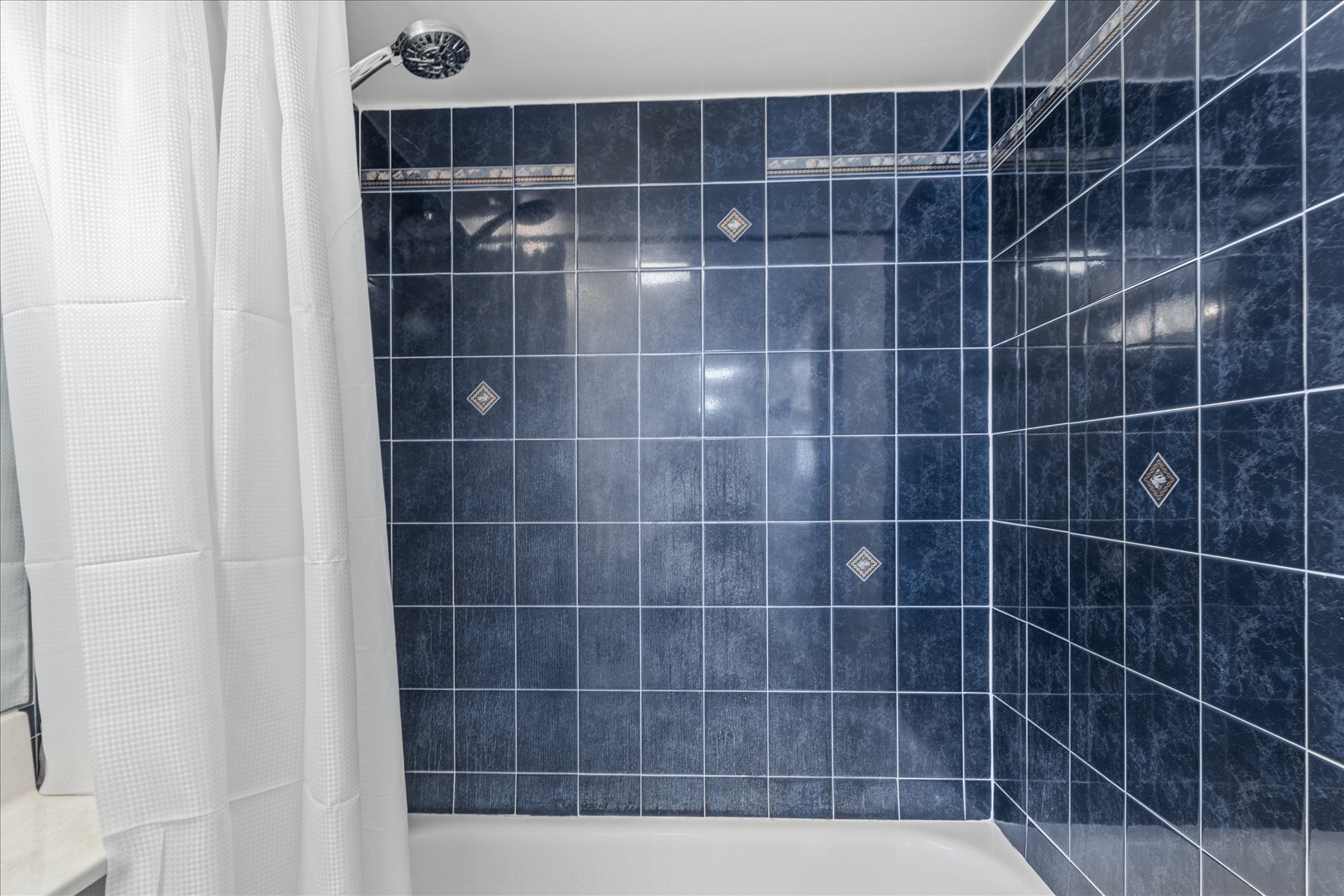 Wash off the salt and sand in this vibrant, deep-blue tiled tub and shower combination.