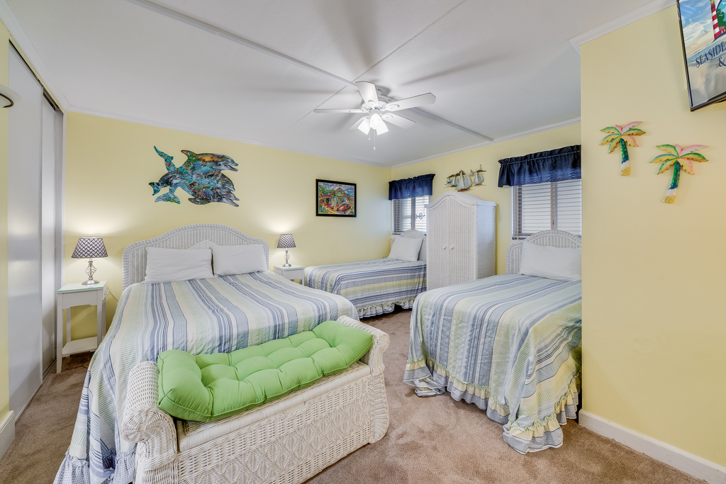A coastal bedroom featuring two twin beds and one queen bed with crisp striped linens.