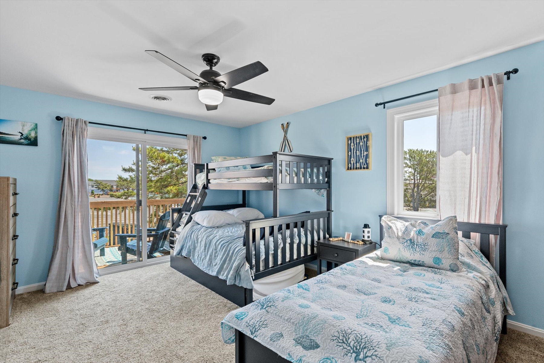 Step right out onto the sun-drenched deck from this bright guest bedroom featuring a cooling ceiling fan.