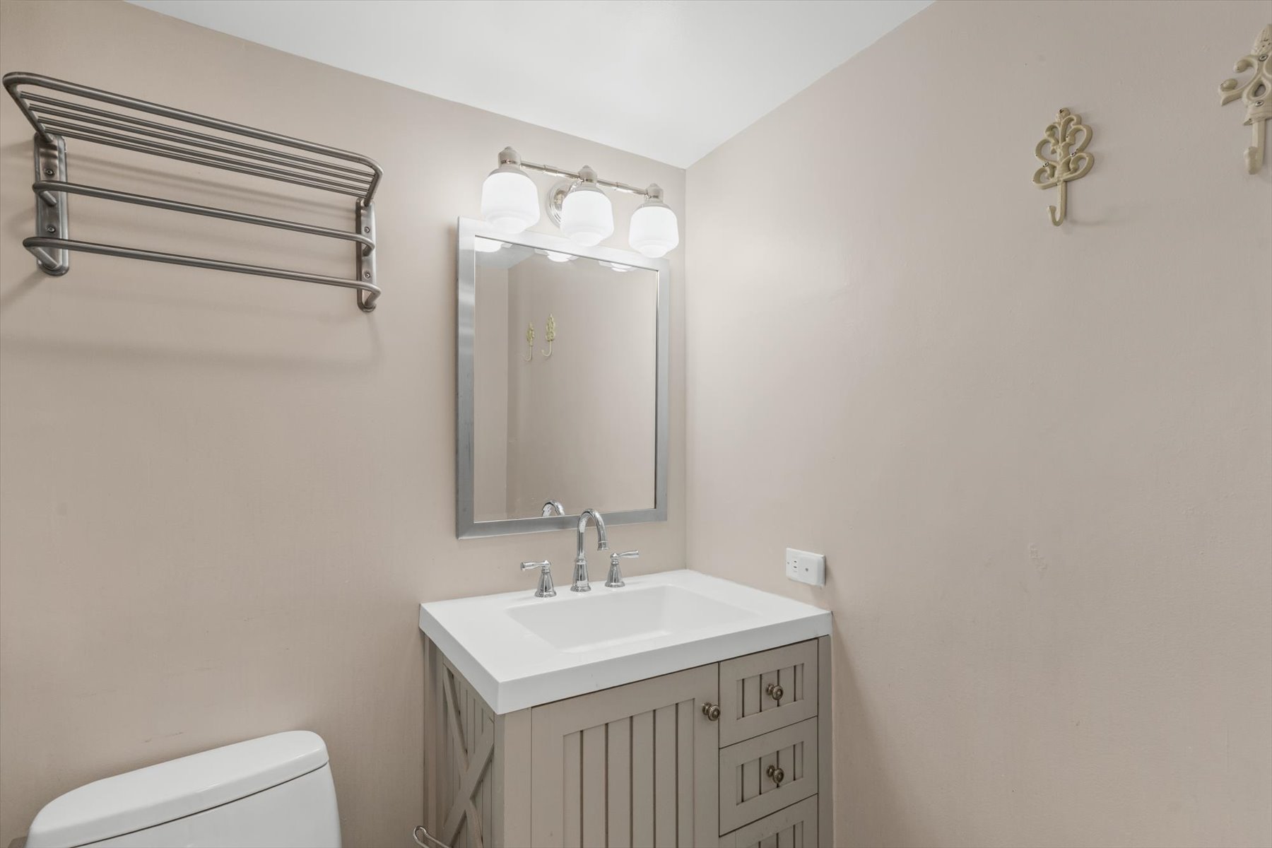 The clean guest bathroom features a modern vanity, a large framed mirror, and bright vanity lighting.