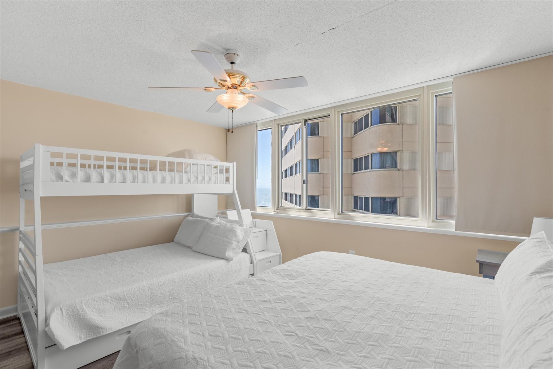 This spacious, light-filled bedroom features flexible sleeping arrangements and big windows showcasing local views.