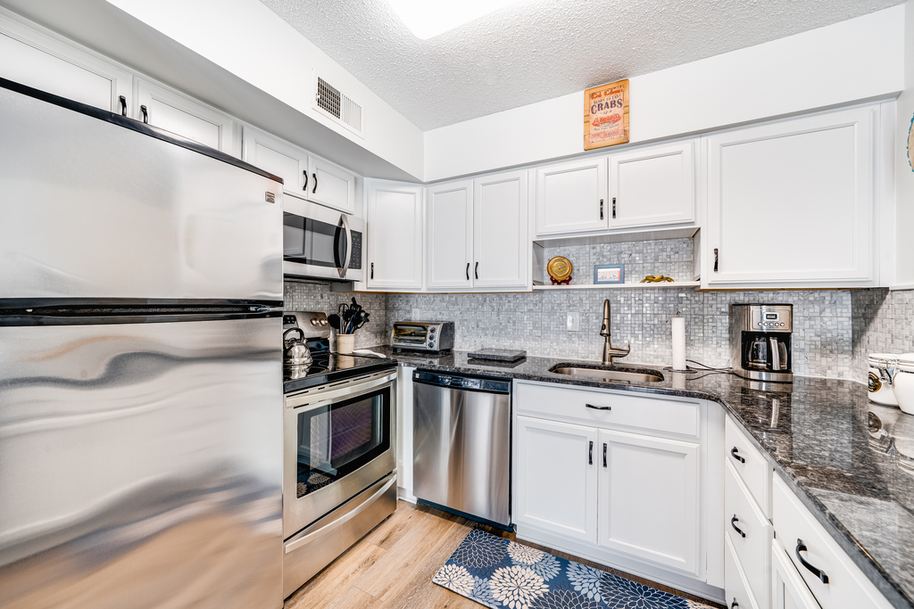 Stainless Steel Appliances and Bright, White & Beachy Cabinetry throughout the Kitchen.