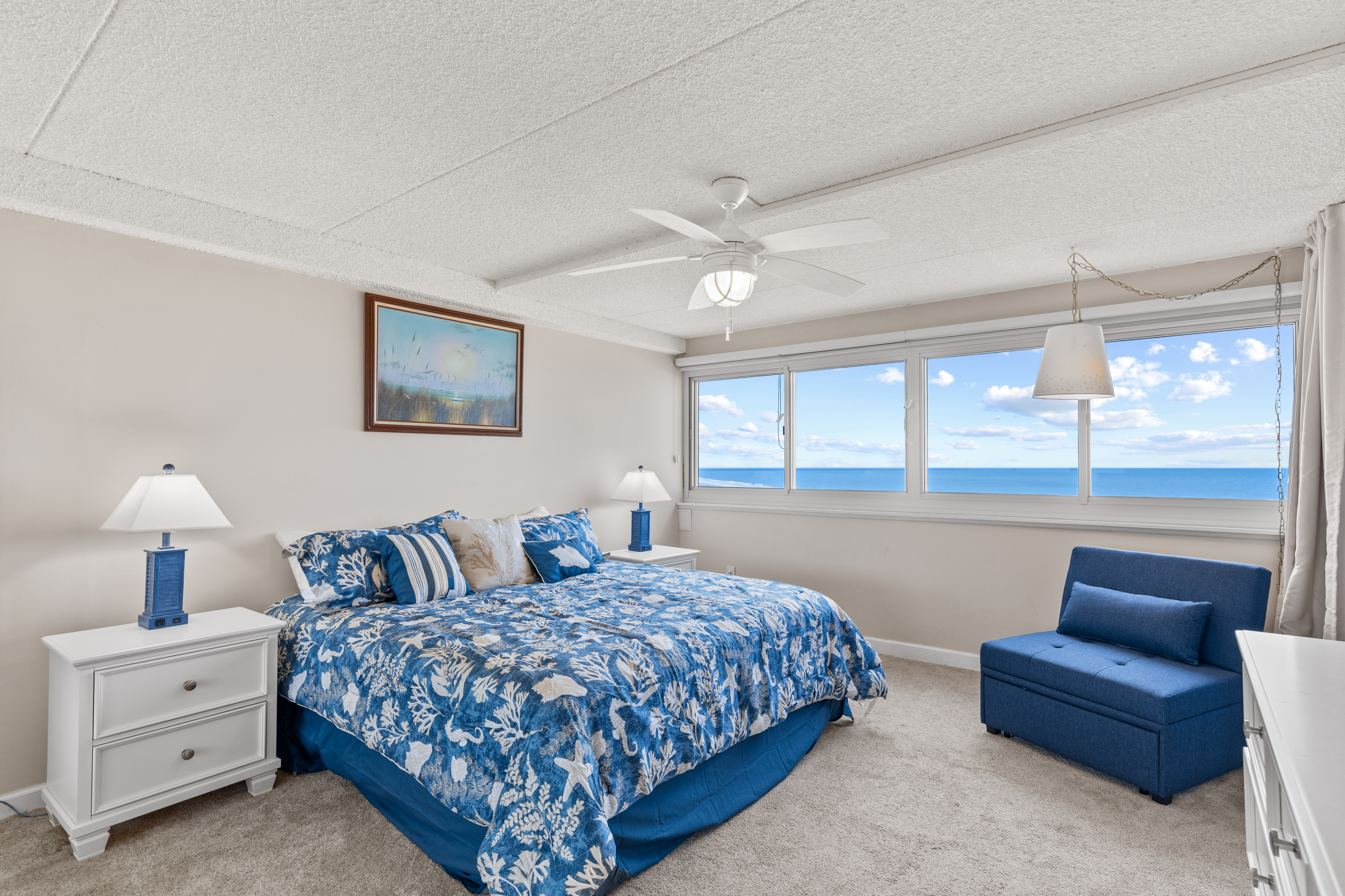 The Primary Bedroom boasts ocean views and cozy blue bedding.