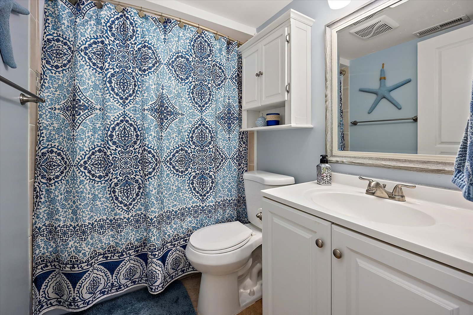 This clean and modern bathroom features a spacious variety and a stylish patterned shower curtain.