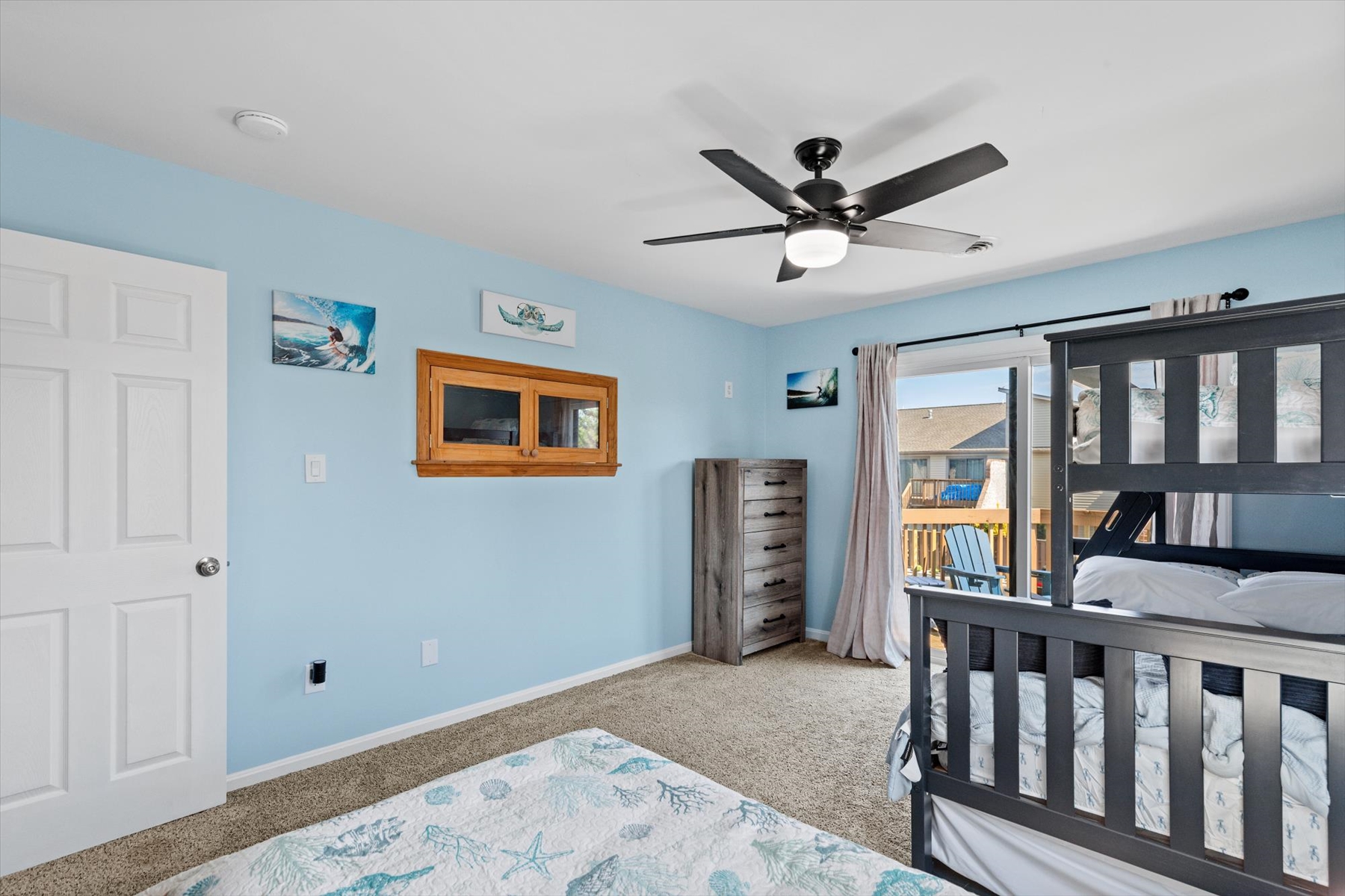 Sliders open wide to bring fresh air and sunshine into this soft-blue bedroom suite, equipped with ample floor space and a dresser.