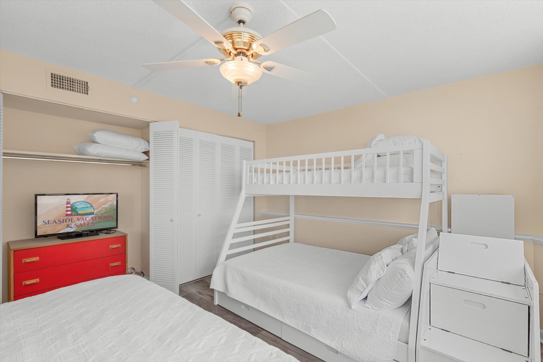 Another angle of this wonderful room highlighting the sturdy bunk bed frame, and a built-in closet, and a ceiling fan.