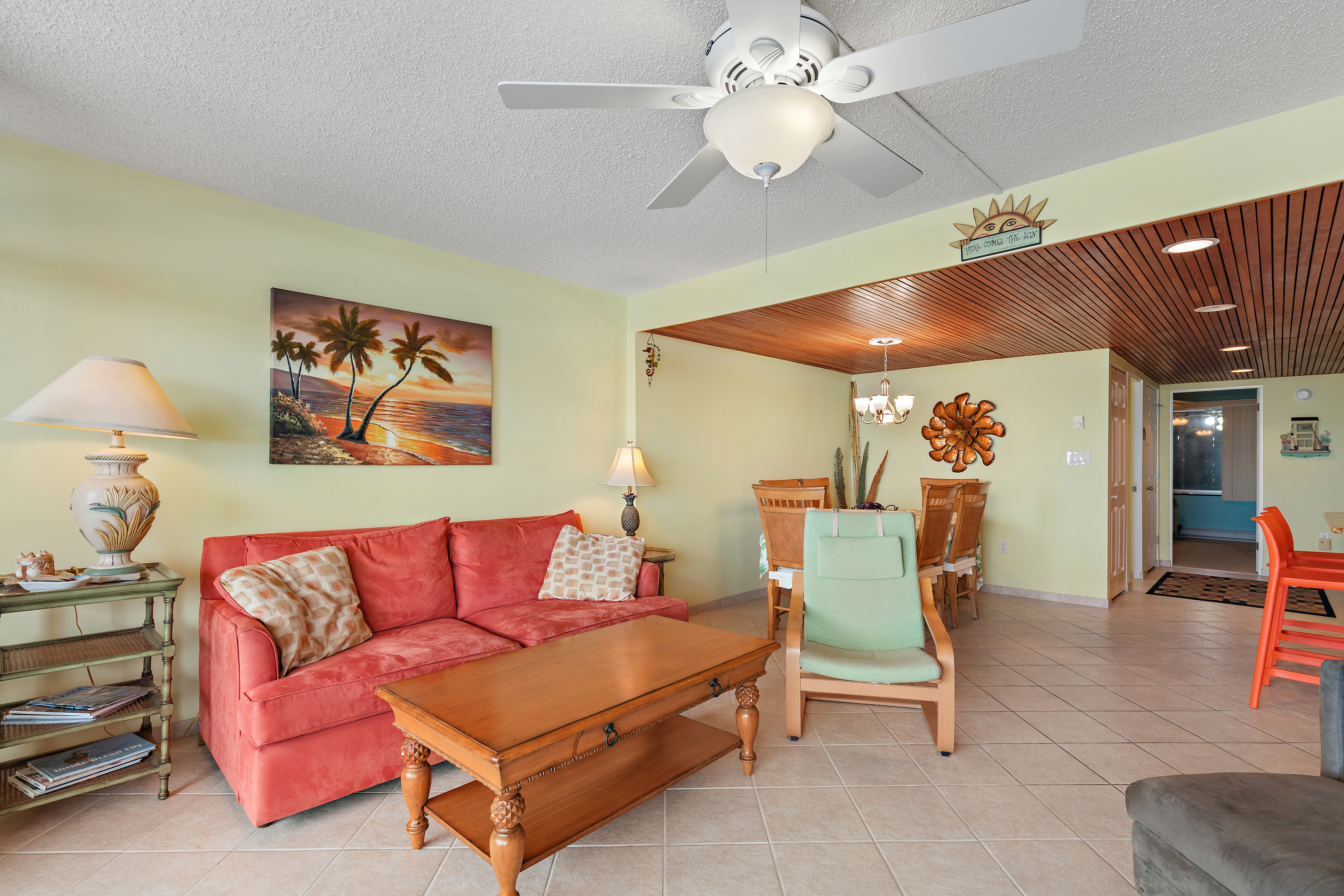 A cozy living-dining area featuring a Sleeper sofa, and beach-themed decor. Soft green walls and tiled floors complete the serene ambiance.