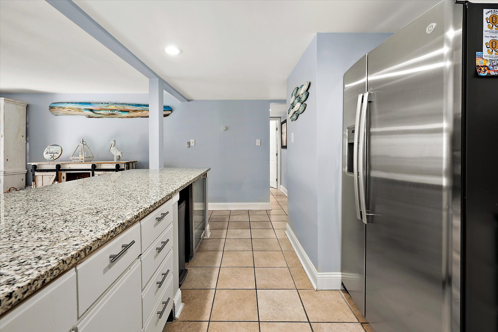A bright and clean corridor layout features a premium stainless steel refrigerator and ample storage space.