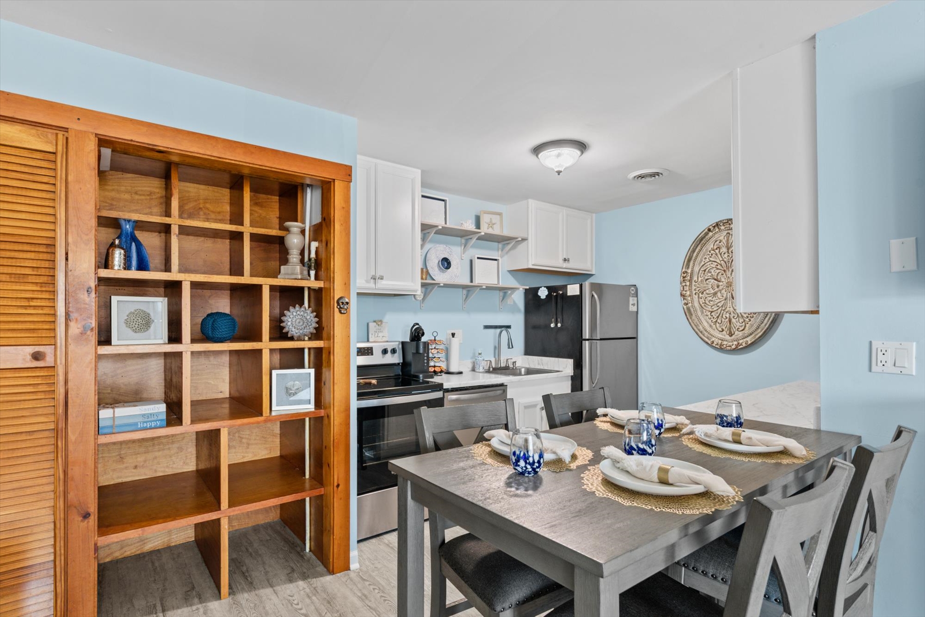 The spacious dining set sits adjacent to a fully equipped kitchen featuring modern black appliances.
