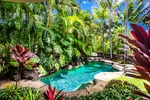 Lush tropical garden surrounds a serene pool for ultimate outdoor relaxation.