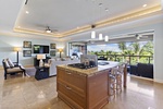 Open kitchen with granite island, cozy living area with TV, and a lanai offering tropical views.