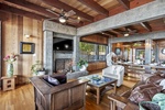 The great room showcases handcrafted timber beams, warm natural finishes, and seamless indoor-outdoor living with panoramic ocean views at every turn.