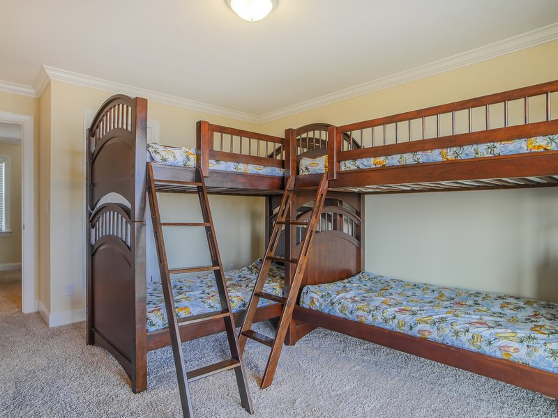 First floor guest bedroom with two twin bunk beds, flat-screen TV, and oceanfront deck access