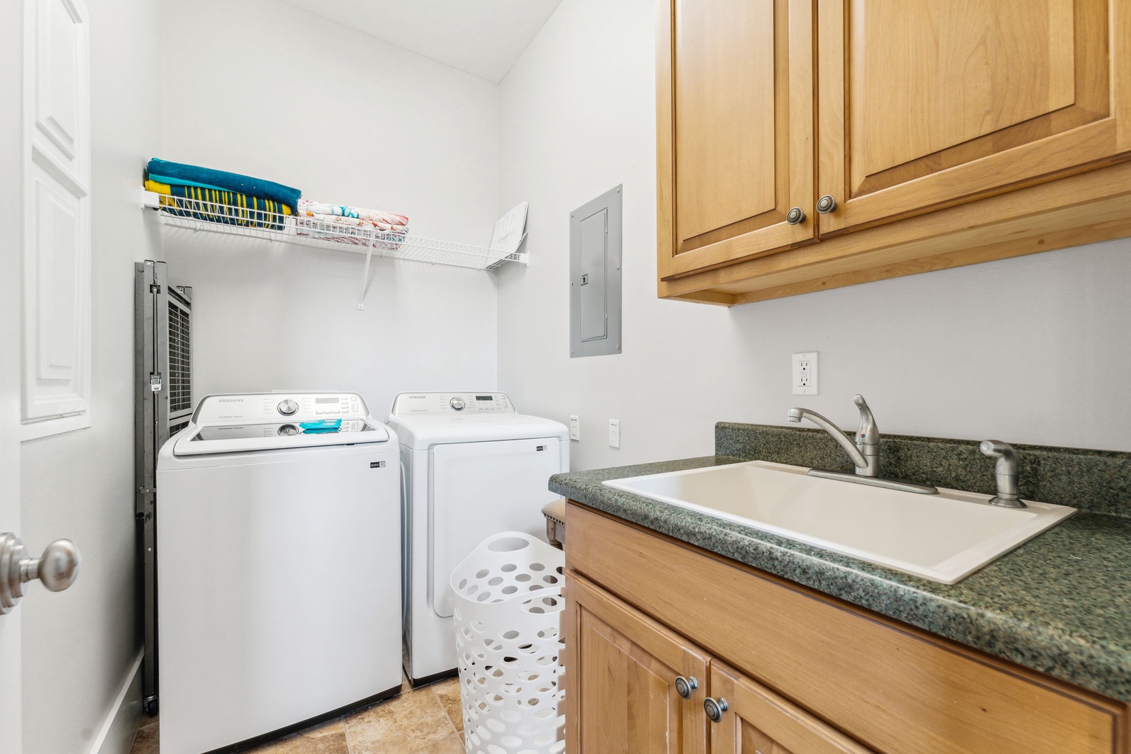 Laundry room on the first floor with washer dryer, sink and cabinets
