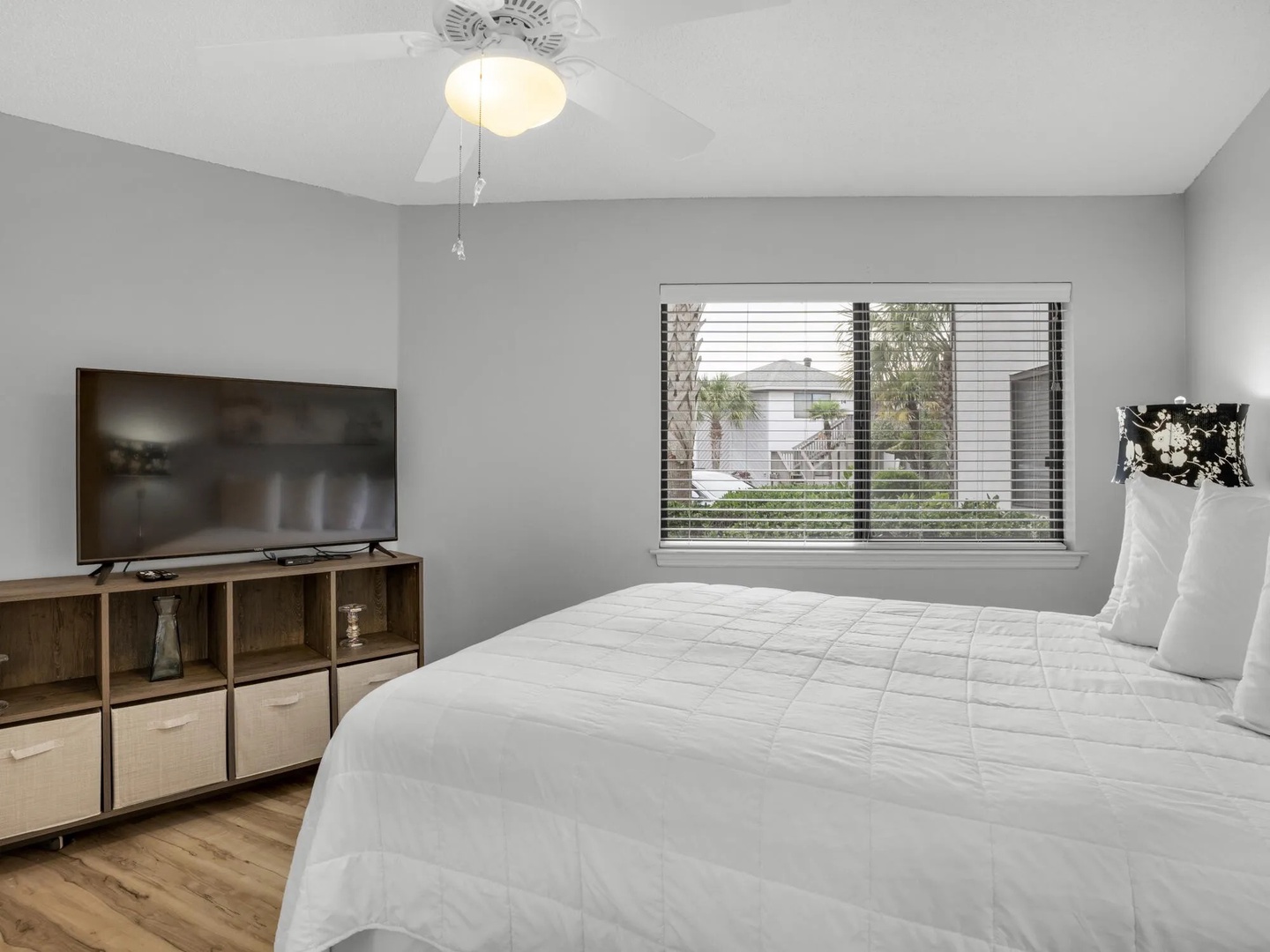 Second bedroom with queen bed, vanity table, and TV.